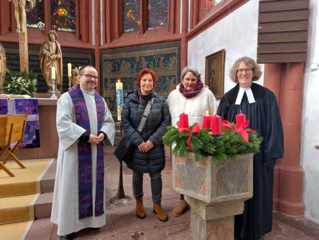 Pfarrerin Vincent und Diakon Rothmann mit der Vertrauensperson des Kirchenvorstandes und der neu eingeführten Kirchenvorsteherin um den Taufstein der Deutschhauskirche.