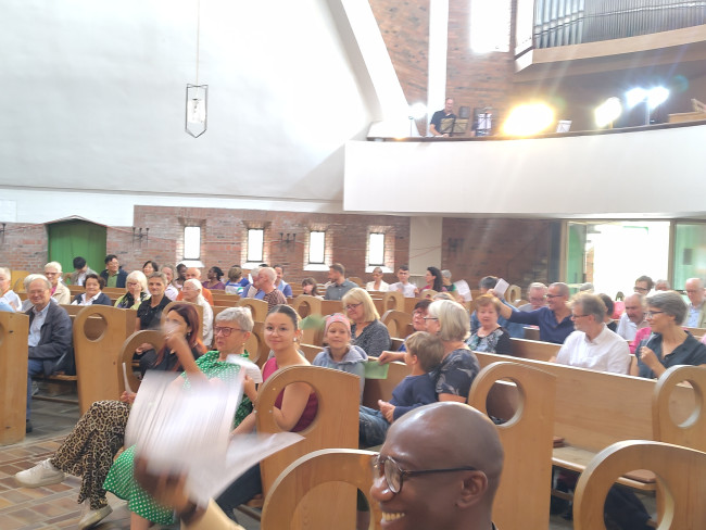 Gottesdienstgemeinde, die sich die Luft zufächelt. 