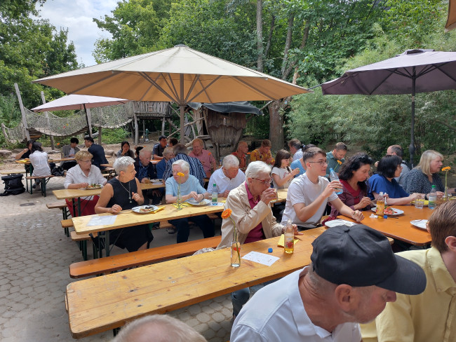 Besucher des Gemeindefestes sitzen an Bierbänken im Garten der Erlöser-Kita 