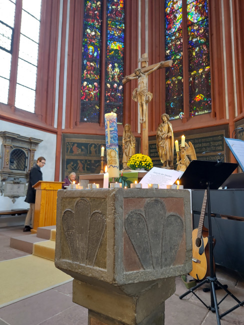 Angezündete Kerzen auf dem Taufstein als Zeichen für das Gebet für den Glauben.