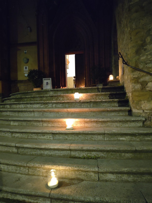 Die Treppe vor der Schönen Pforte der Deutschhauskirche vor der Feier der Osternacht: Nur mit Kerzen beleuchtet und einem hellen Schein hinter der Kirchentür