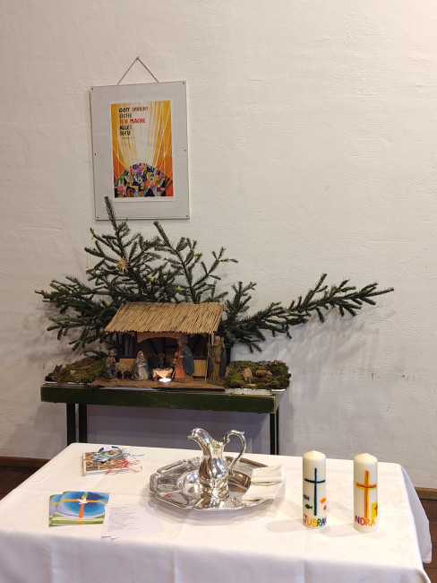 Taufschale und Taufkerzen auf einem Tisch vor der Krippe im Remter.